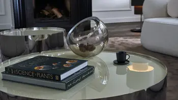 Moderner Couchtisch „Toffee“ von Bielefelder Werkstätten mit hochglänzender Oberfläche und runder Form, dekoriert mit einem Buch, einer Glaskugel und Espressotasse – stilvoll inszeniert in einem eleganten Wohnambiente, erhältlich bei himmlisch wohnen.